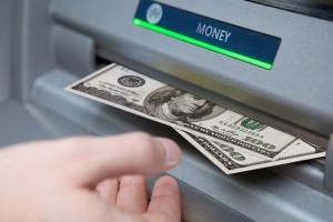 An ATM transaction showing a person receiving two one-hundred dollar bills.